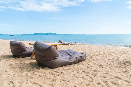 Two bean bags and outdoor table on the sand beach.