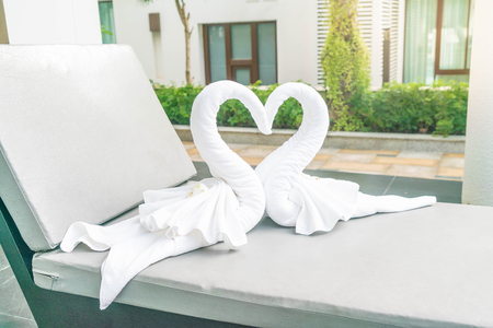 close up view of two nice towels swans on bed pool - with sunflare effectの写真素材