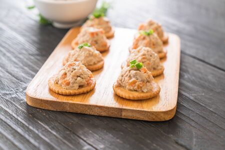 tuna spread with cracker on wood board