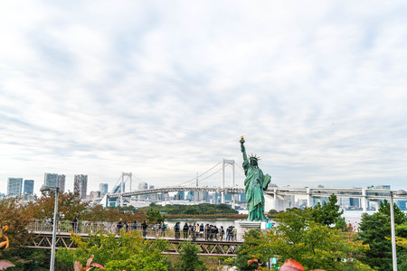 TOKYO - November 16 2016: A crowd of tourists and locals enjoy the view of the Tokyo Bay from Odaiba on a cloudy Autumn afternoon, with the statue of liberty in the foreground, on November 16, 2016のeditorial素材