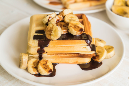 banana waffle with chocolate on white plateの写真素材