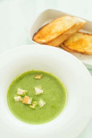 spinach soup with garlic bread on tableの写真素材