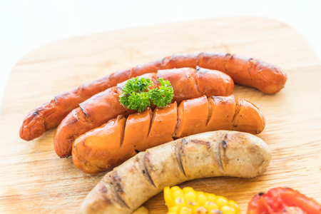 mix grilled sausage with vegetables and french fries on wood boardの写真素材