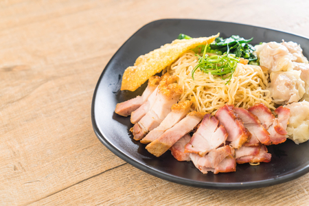 Egg noodle with red roast pork, crispy pork, dumplings, soup and condimentsの写真素材