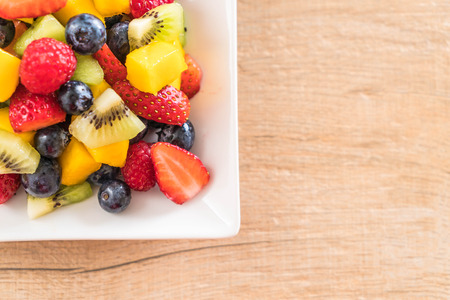 mixed fresh fruits (strawberry, raspberry, blueberry, kiwi, mango) on white plateの写真素材