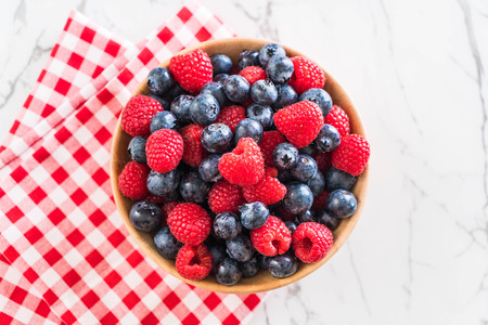 fresh blueberry and rasberry on wood bowlの写真素材