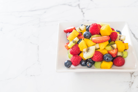 mixed fresh fruits (strawberry, raspberry, blueberry, kiwi, mango) on white plateの写真素材