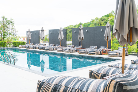 Beautiful luxury umbrella and chair around outdoor swimming pool in hotel and resort