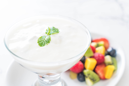 yogurt with mixed fruit (strawberry, blueberries, raspberry, kiwi, mango) on white plateの写真素材