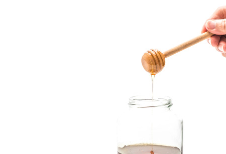 Honey drip in jar on white backgroundの写真素材