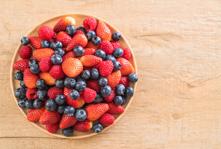 fresh blueberry, strawberry and rasberry on wood plateの写真素材