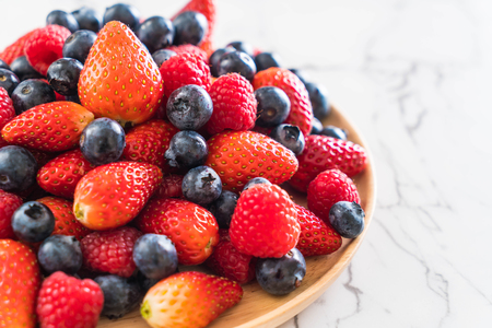 fresh blueberry, strawberry and rasberry on wood plateの写真素材