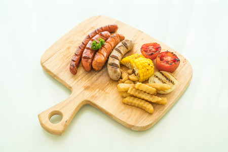 mix grilled sausage with vegetables and french fries on wood boardの写真素材