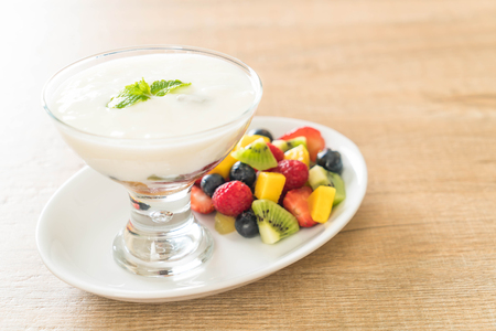 yogurt with mixed fruit (strawberry, blueberries, raspberry, kiwi, mango) on white plateの写真素材