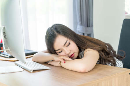 lazy asian woman sleeping in office - business conceptの写真素材