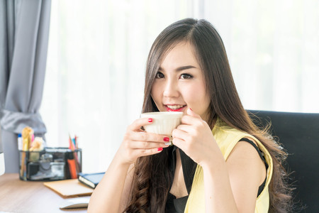 asian business woman happy with coffee cup in officeの写真素材