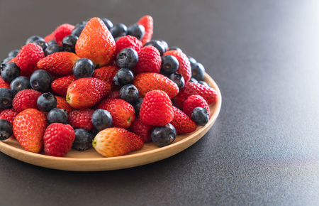 fresh blueberry, strawberry and rasberry on wood plateの写真素材