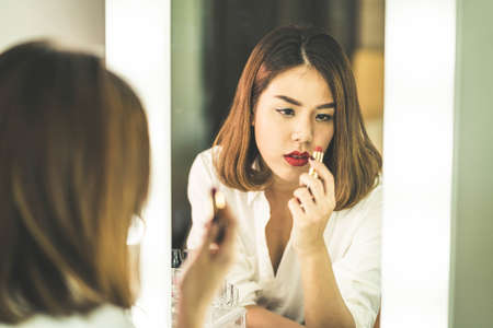 Young Beautiful Asian Woman making make-up near mirror - vintage effect filter
