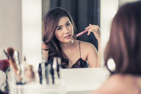 Young Beautiful Asian Woman making make-up near mirror - vintage effect filterの写真素材