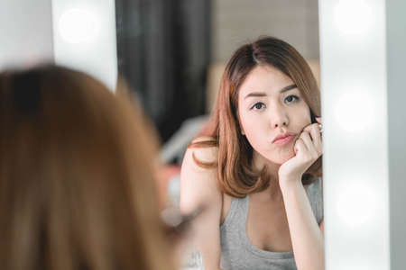 Young Beautiful Asian Woman making make-up near mirror - vintage effect filterの写真素材
