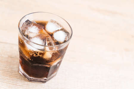 glass of cola with ice on the tableの写真素材