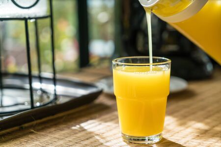 pouring orange juice in a glass - selective focus pointの写真素材
