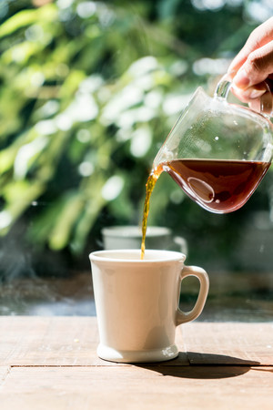 pouring hot coffee in cupの写真素材