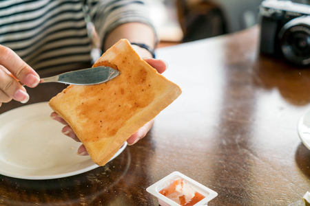 Hand holding bread and Strawberry jam making for breakfast - selective focus pointの写真素材