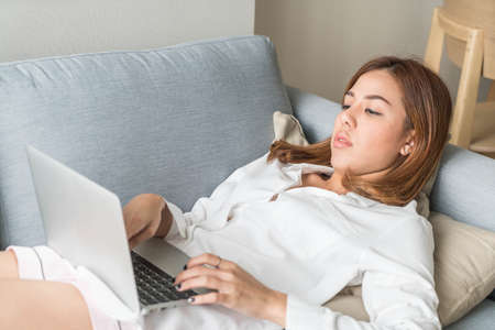 Beautiful asian woman working at home with laptop and telephoneの写真素材