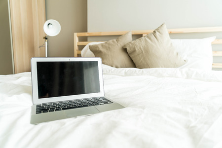 laptop on white bed in morningの写真素材