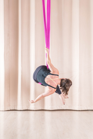 Asian woman training in a fitness room with fly yoga elementsの写真素材