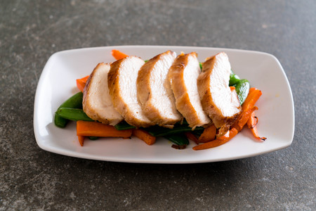 grilled chicken with green peas and carrot on tableの写真素材