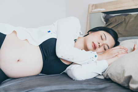 Young beautiful Asian pregnant woman  sleeping on bed  - selective focus point and vintage  styleの写真素材