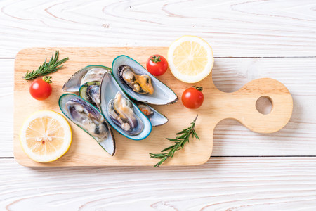 fresh mussels on wooden board with ingredients
