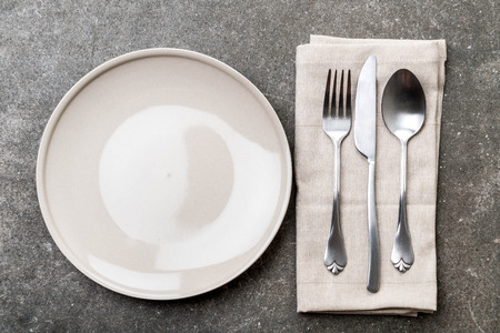 empty plate spoon fork and knife on tableの写真素材