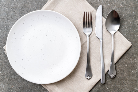 empty plate spoon fork and knife on tableの写真素材