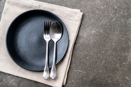 empty plate spoon fork and knife on tableの写真素材