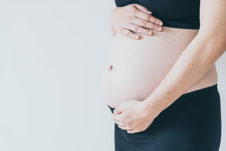 Belly of pregnant woman with hands - selective focus point with vintage filter styleの写真素材