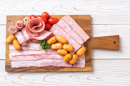 bacon, sausage, smoked ham and barbecue bacon on wood board