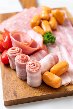 bacon, sausage, smoked ham and barbecue bacon on wood boardの写真素材