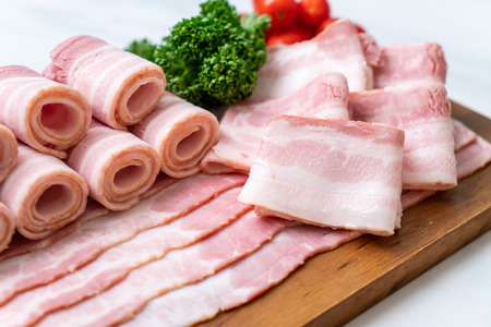 sliced raw pork bacon on wood boardの写真素材