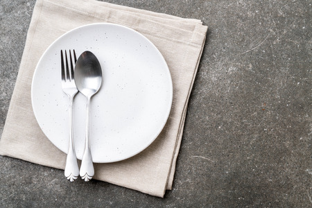 empty plate spoon fork and knife on tableの写真素材