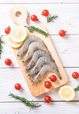 fresh shrimps or prawns raw on wooden board with ingredientsの写真素材