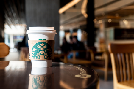 BANGKOK, THAILAND - June 29, 2018: Starbucks hot beverage coffee with holder on the table in Starbuck coffee shop.のeditorial素材