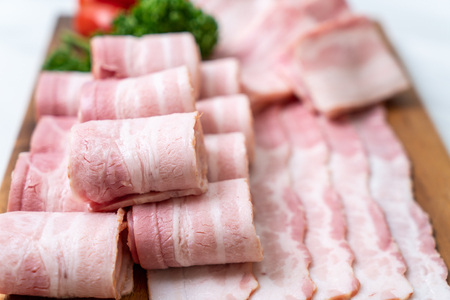 sliced raw pork bacon on wood boardの写真素材