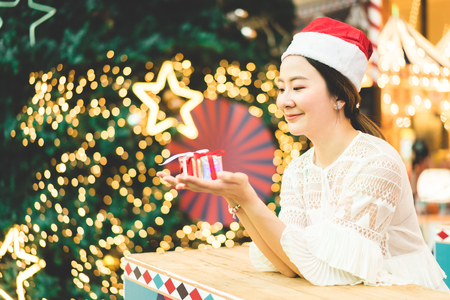 portrait of smiling beautiful young Asian woman with gift on the festive Christmas fair - vintage effect filterの写真素材