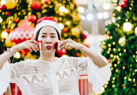 portrait of smiling beautiful young Asian woman with gift on the festive Christmas fair - vintage effect filterの写真素材
