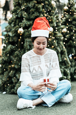 portrait of smiling beautiful young Asian woman with gift on the festive Christmas fair - vintage effect filterの写真素材