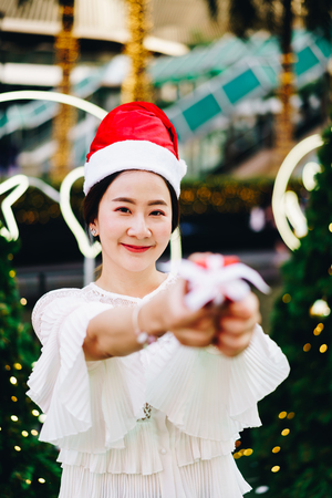 portrait of smiling beautiful young Asian woman with gift on the festive Christmas fair - vintage effect filterの写真素材