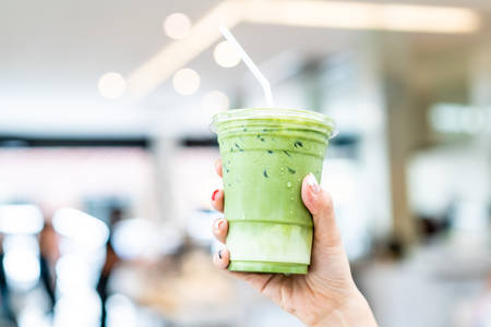 close-up hand holding iced matcha latte green tea cupの写真素材